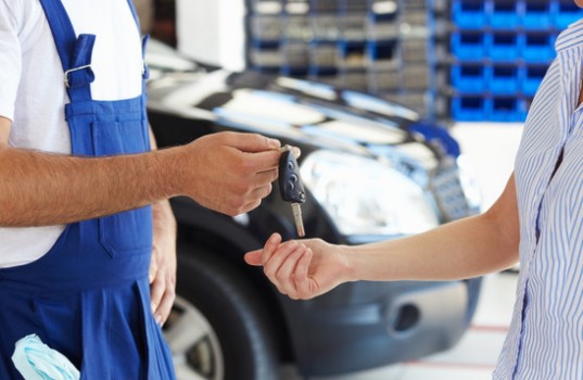 cropped view of mechanic giving car keys to female client